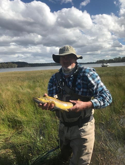 Angler holding a golden brown trout beside a highland lake