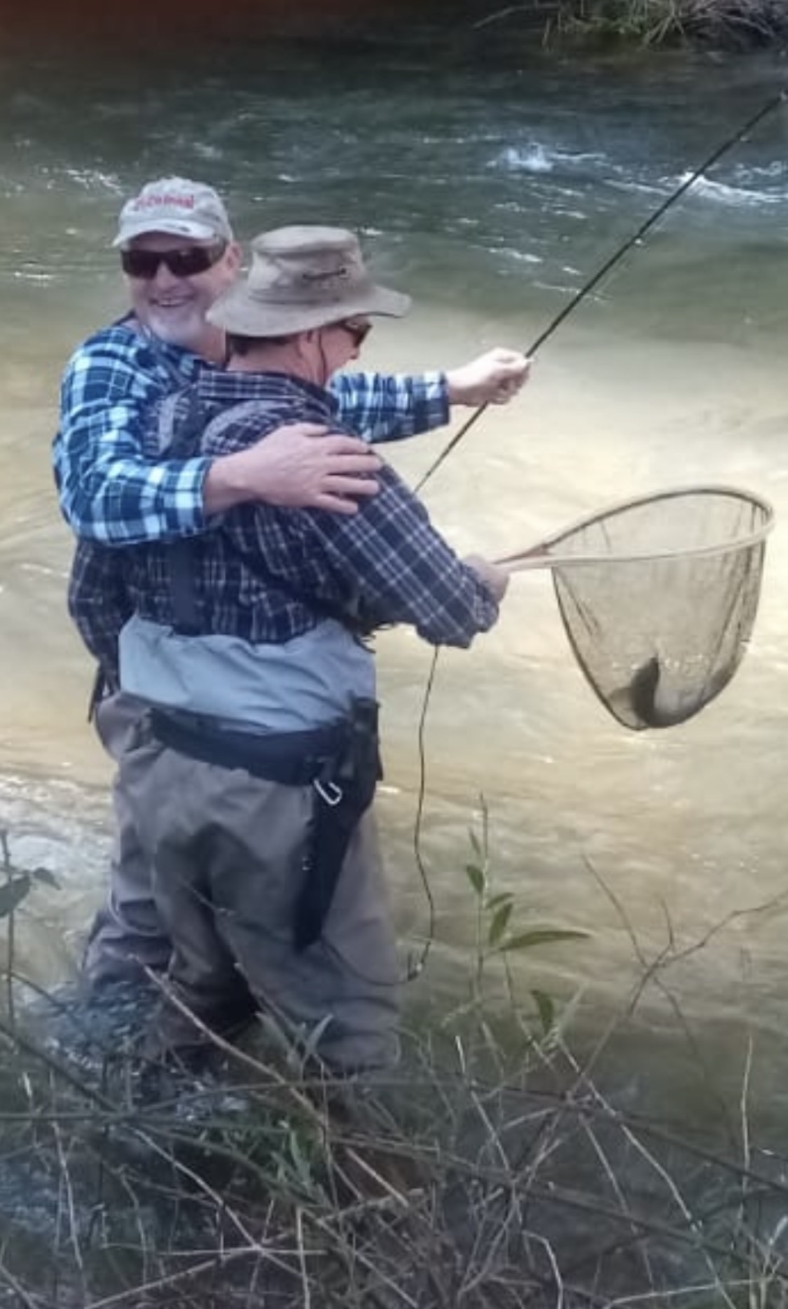 Guide netting a trout for a client mid-river